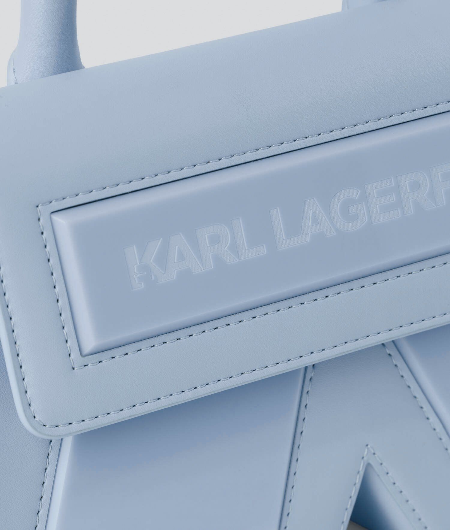 Close-up of a pale blue leather handbag with embossed Karl Lagerfeld lettering and a K-shaped front detail