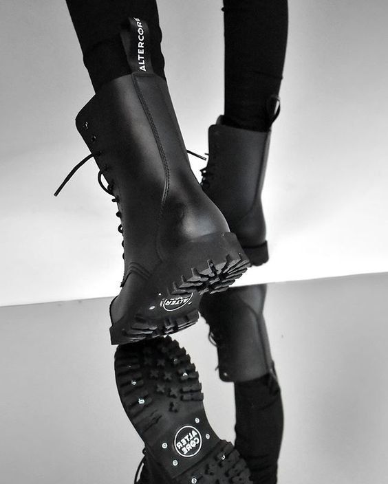 Black-and-white shot of black lace-up Altercore boots on a model, with the sole reflected in a mirror below