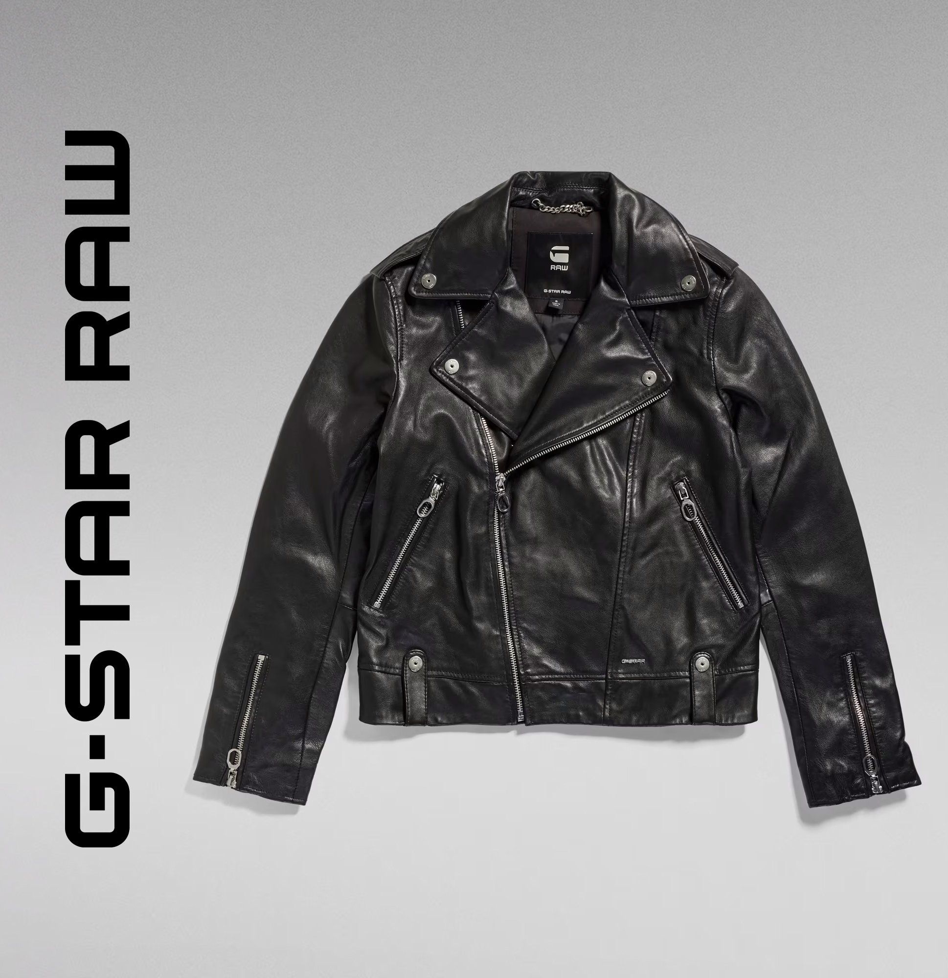 G-Star RAW black leather biker jacket with zip pockets, flat lay on grey gradient background