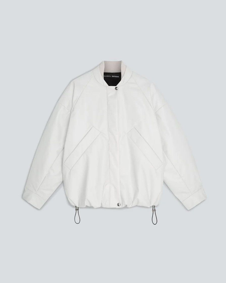 White oversized bomber jacket with drawcord hem, flat lay on pale grey-blue background