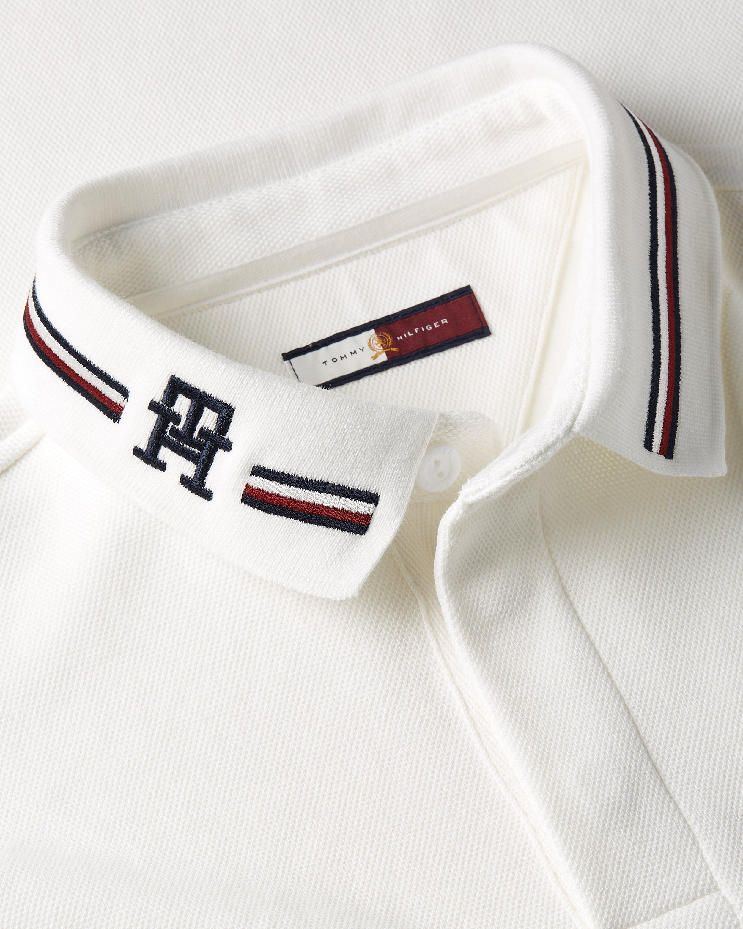 Close-up of a white polo collar with striped trim and TH monogram, Tommy Hilfiger