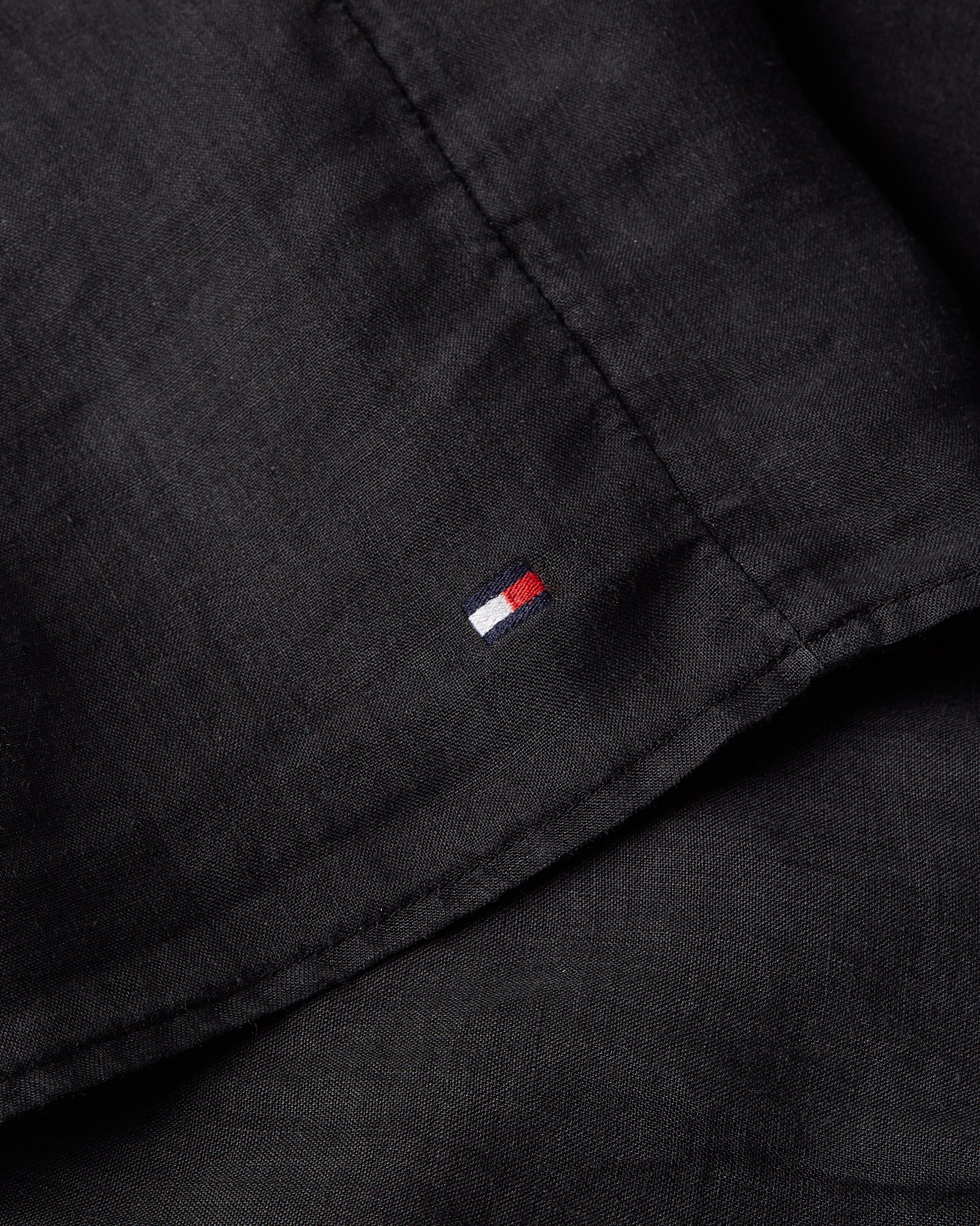 Close-up of a small flag logo on black linen shirt fabric, Tommy Hilfiger