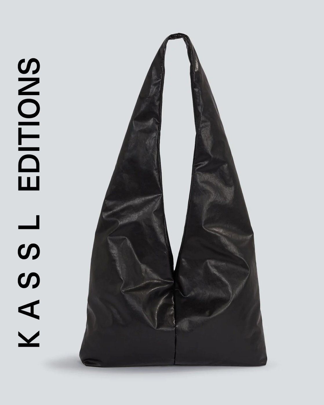 Black glossy slouchy hobo shoulder bag with long strap on pale grey background, Kassl Editions
