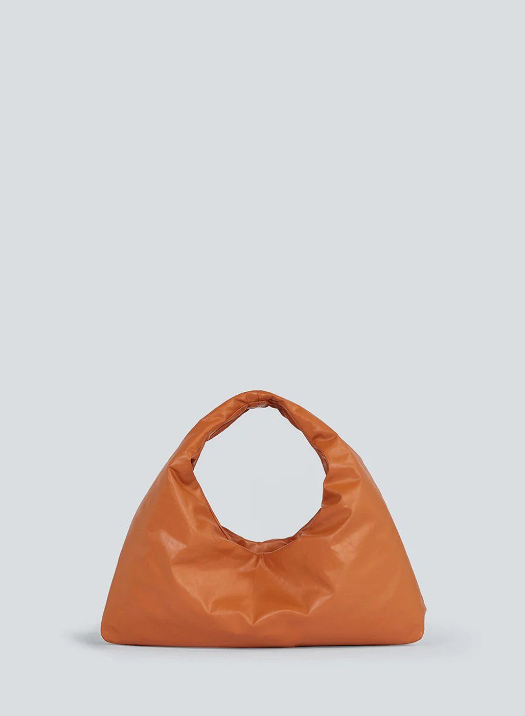 Small orange puffed leather top-handle bag on pale grey background, table top shot with soft shadow